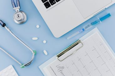 stethoscope-pills-syringe-laptop-and-ecg-medical-report-on-clipboard-over-blue-backdrop2